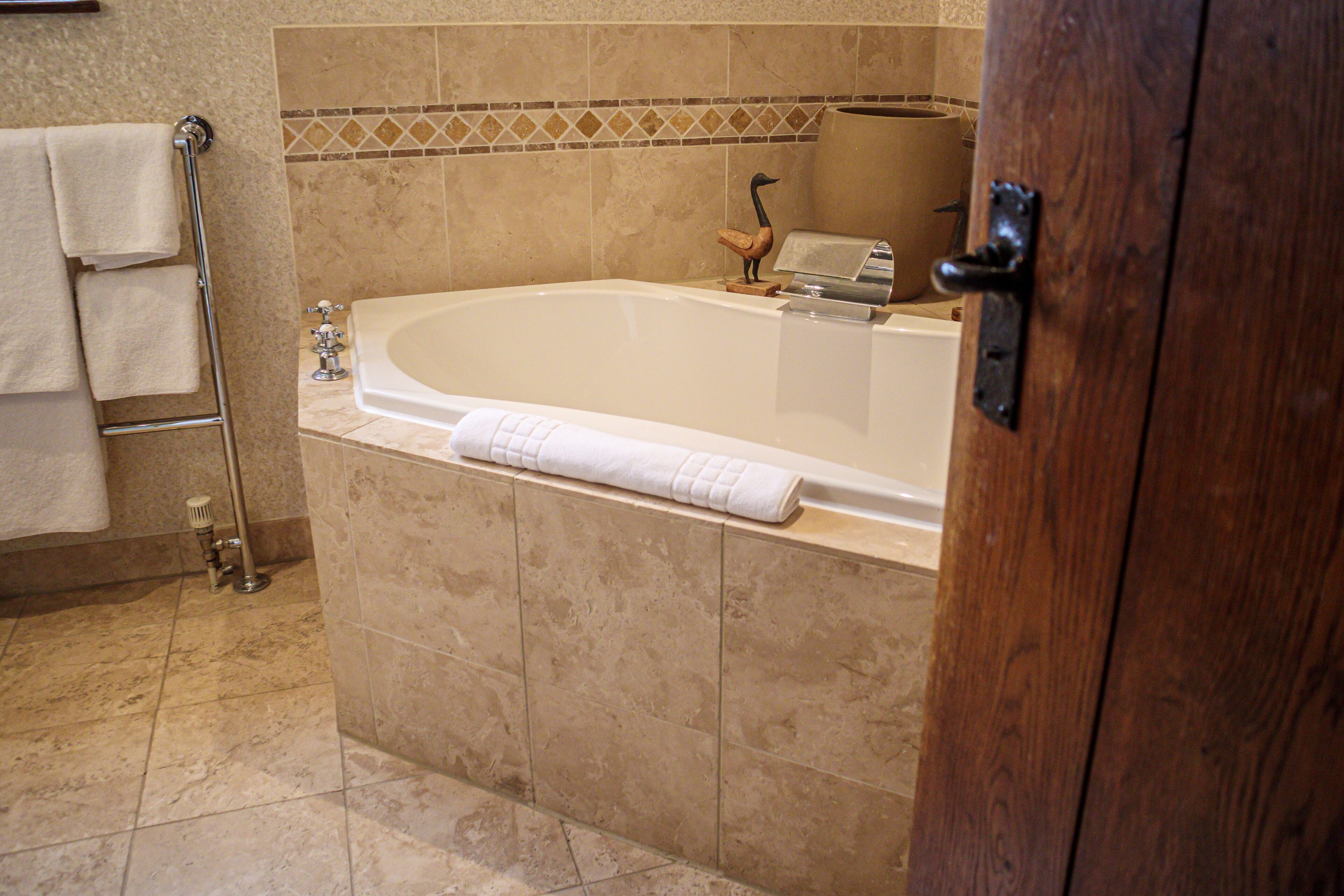 A bathroom with a bathtub, a towel rack, and a wooden door.