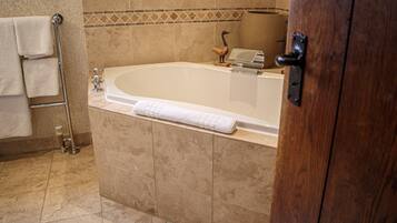 A bathroom with a bathtub, a towel rack, and a wooden door.