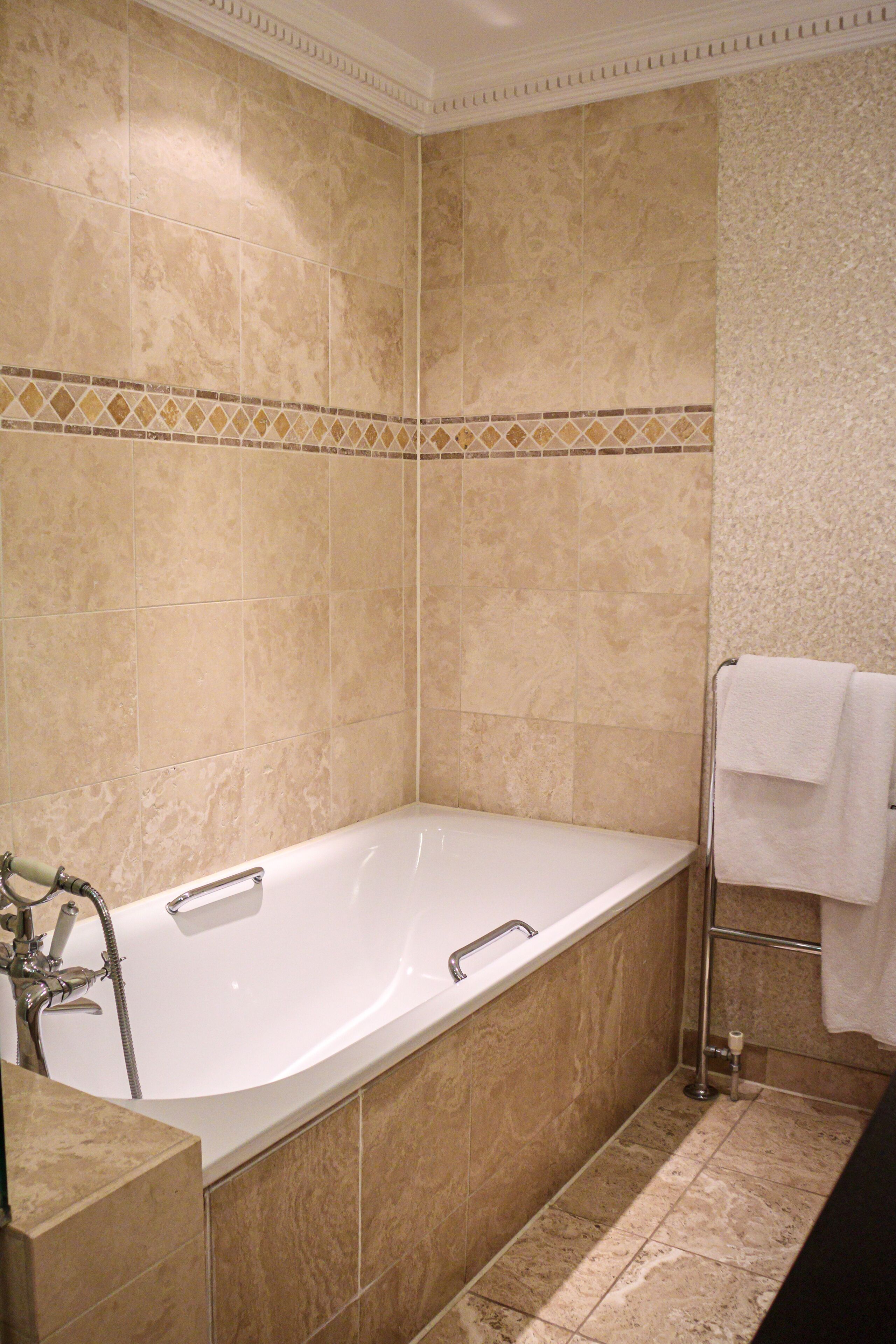 A bathroom with a bathtub, a shower, and a towel rack.