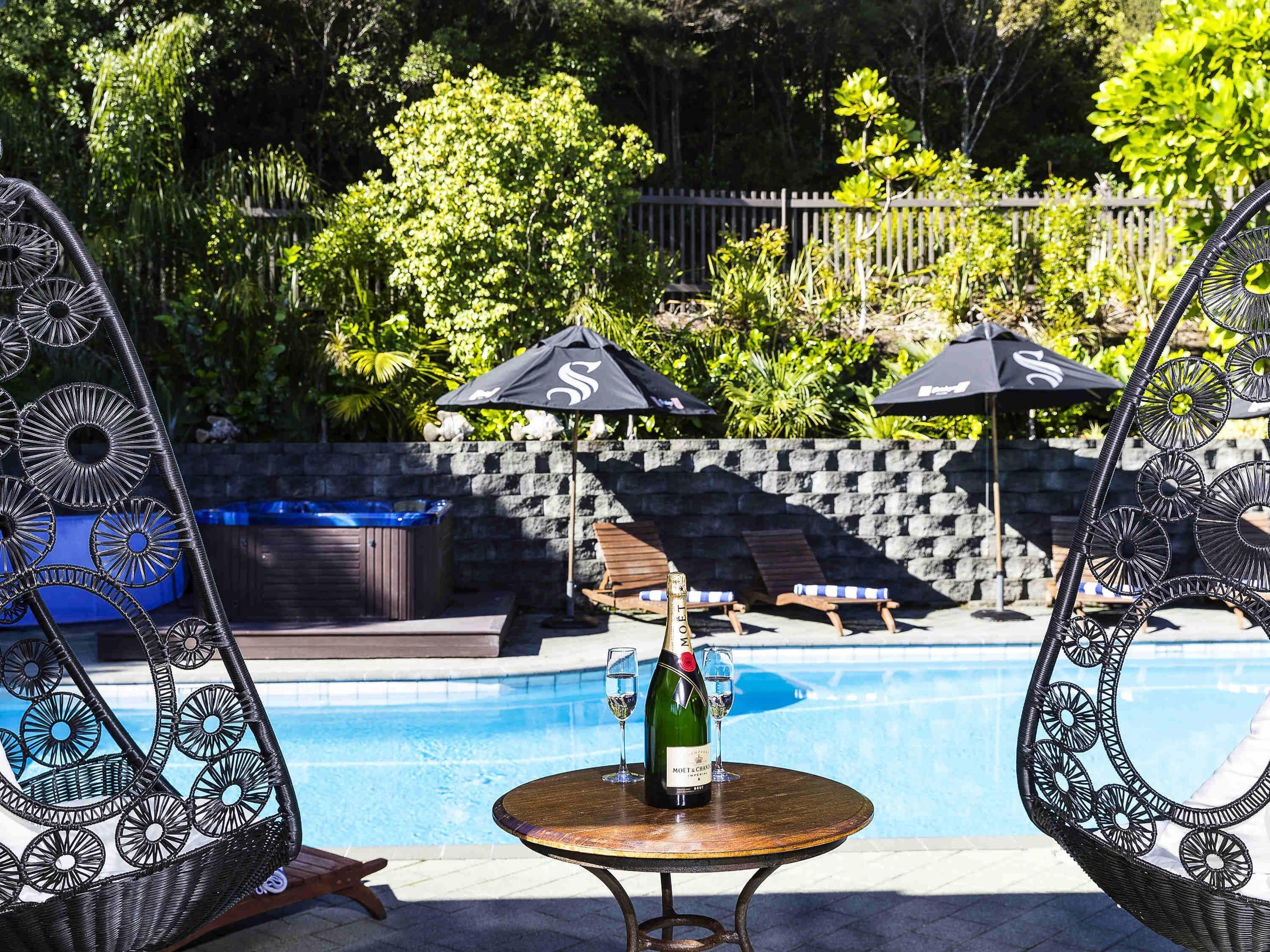 Un área de piscina con jacuzzi, sillas de descanso y sombrillas.