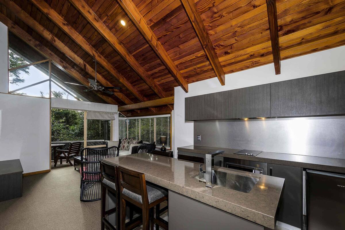Una cocina moderna con techo de madera, ventanas amplias y una zona de bar.