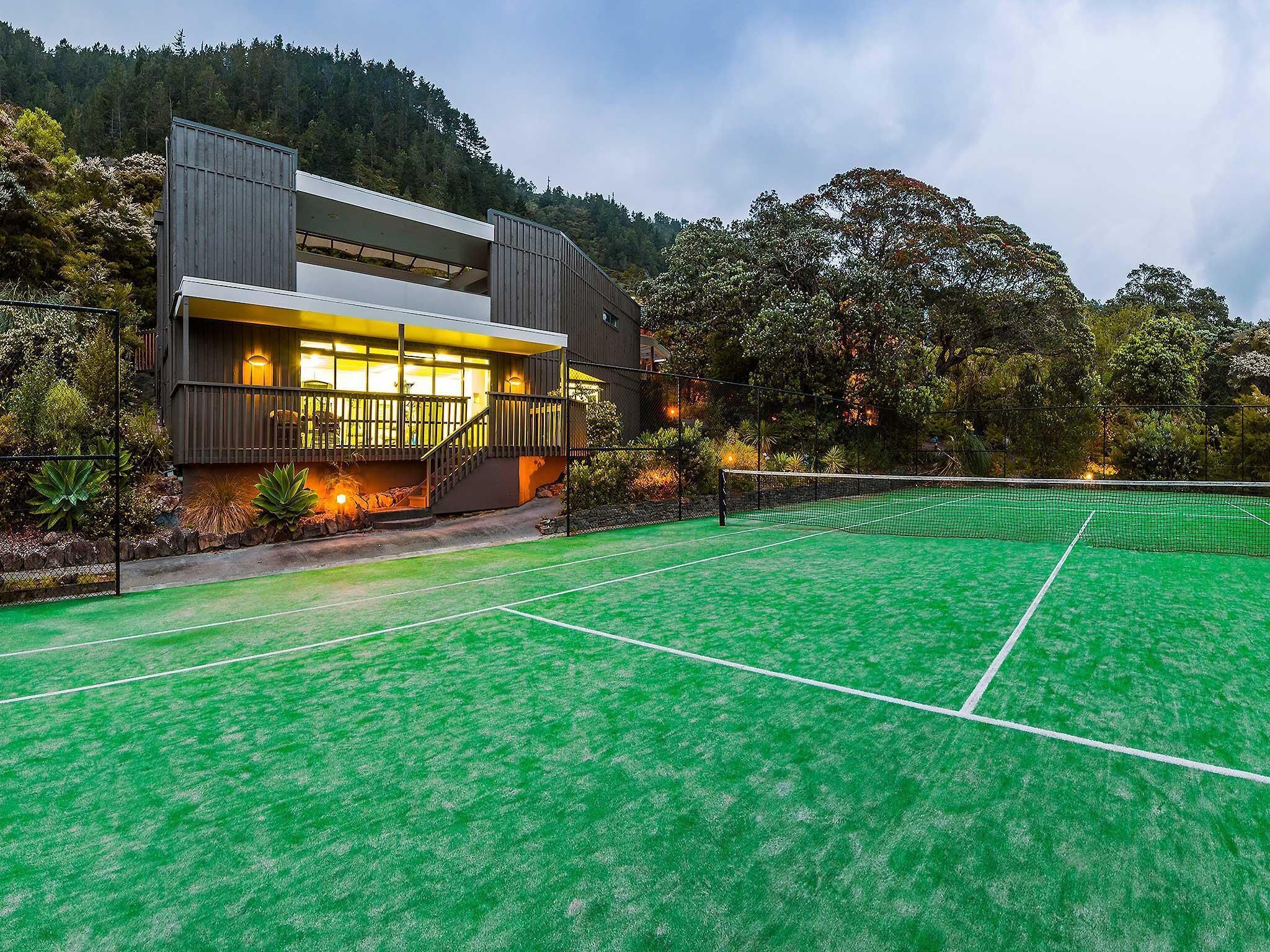 Una cancha de tenis con un edificio moderno contiguo.