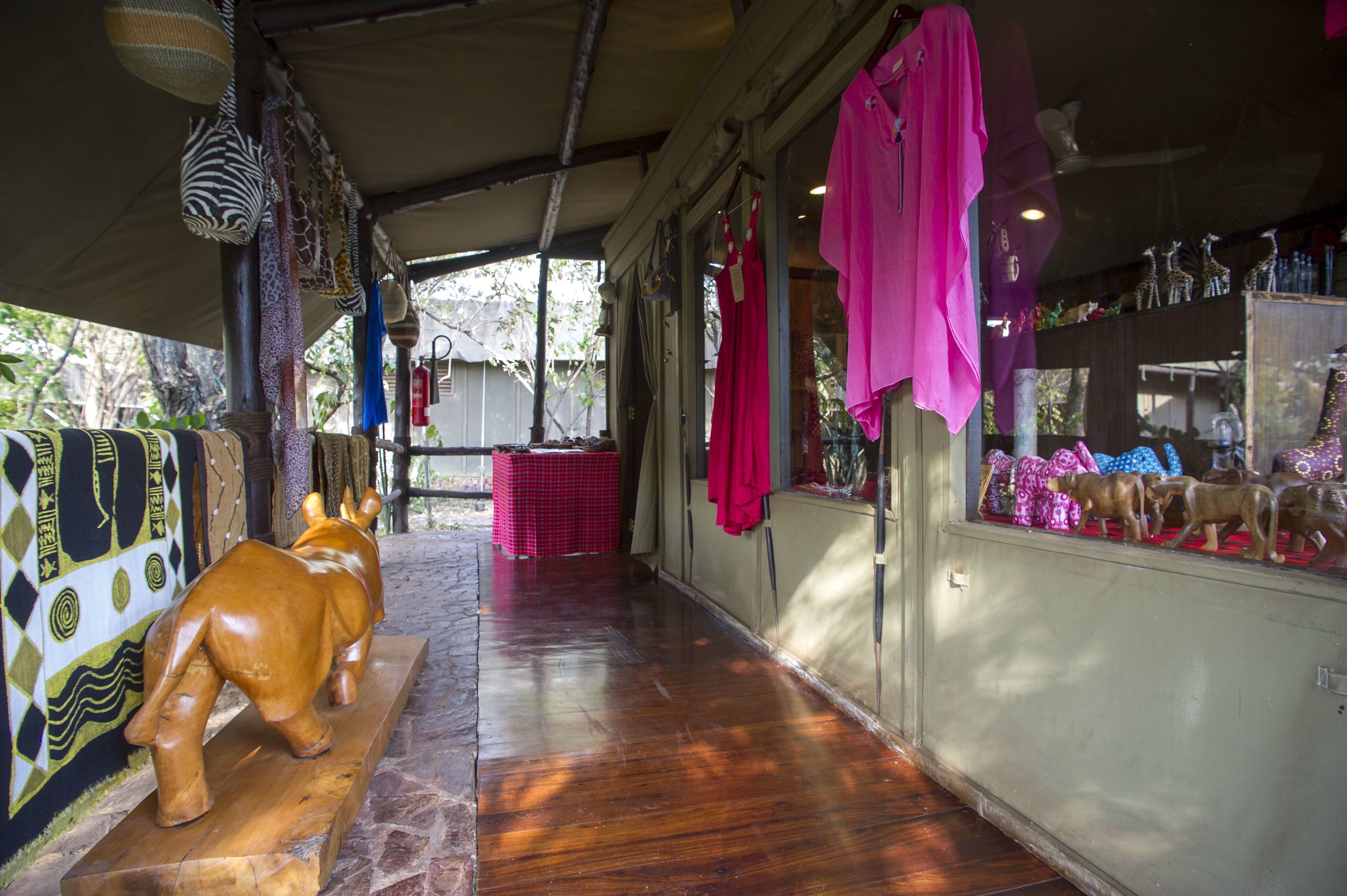 A corridor with a wooden floor, a zebra-patterned wall, and a wooden sculpture of a bull.