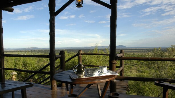 A wooden deck with a table set for tea, overlooking a scenic landscape. - Kirawira Serena Camp (Serengeti)
