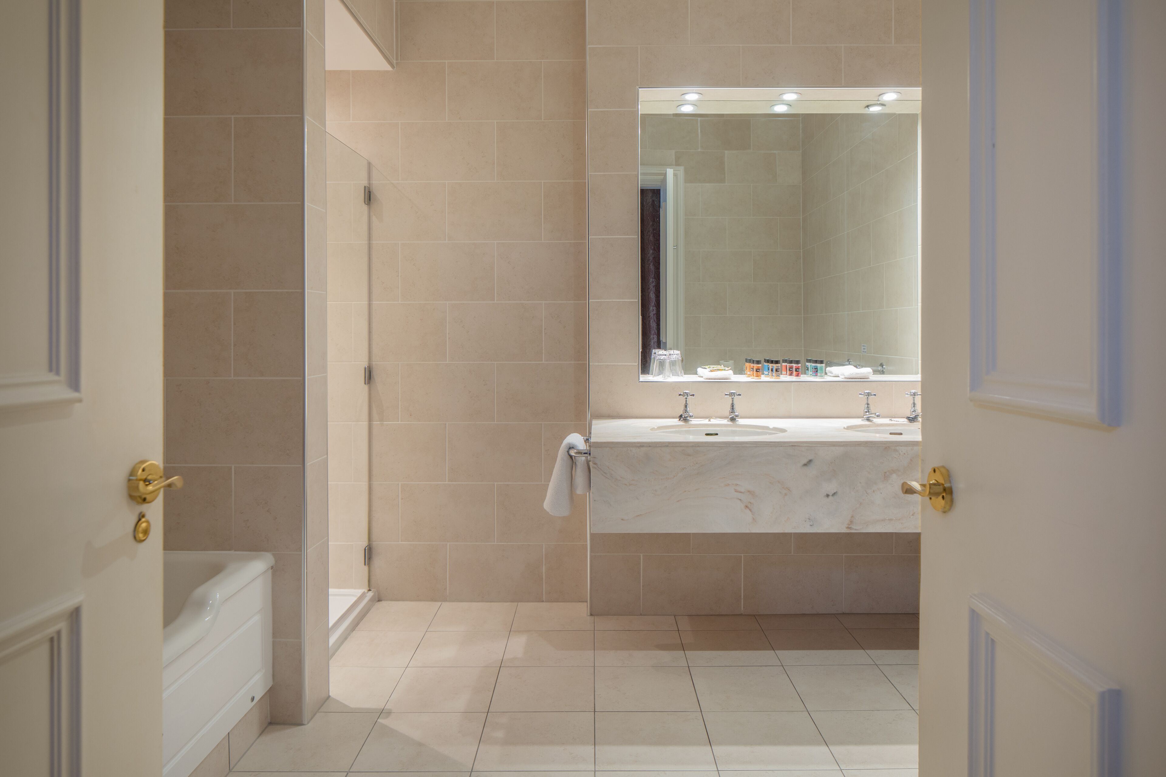 Un bany modern amb un lavabo de marbre, un mirall gran i una dutxa.