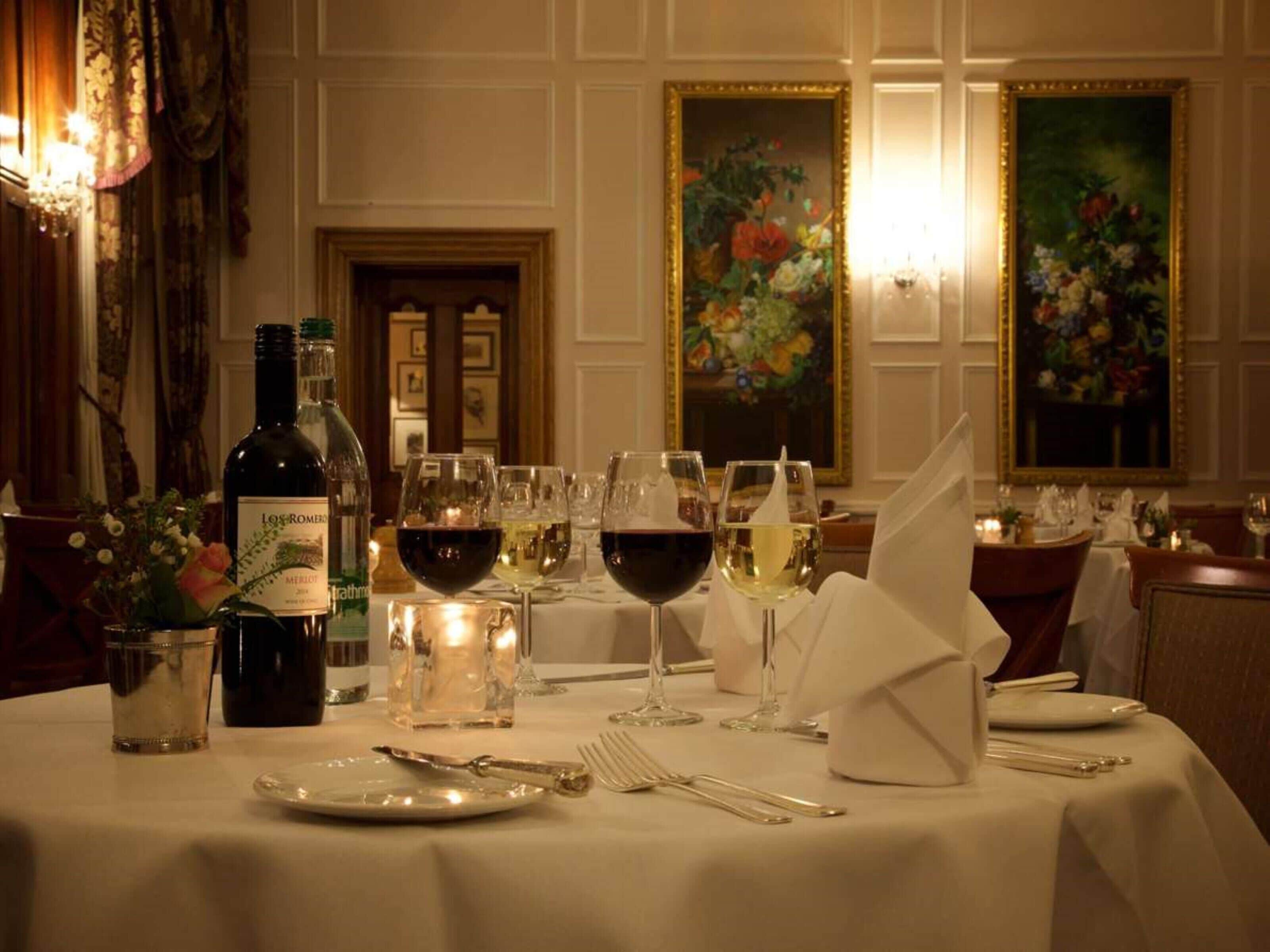 Una mesa puesta con copas de vino, una botella y cubiertos.