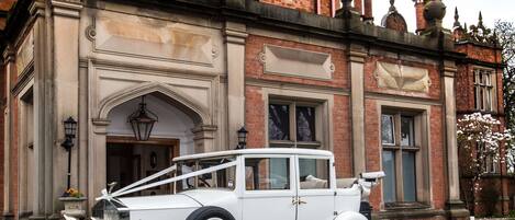 Un coche blanco clásico estacionado frente a un edificio histórico con arquitectura ornamentada.