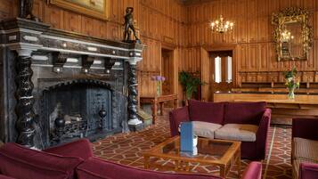 A grand room with a fireplace, wooden paneling, and plush seating.