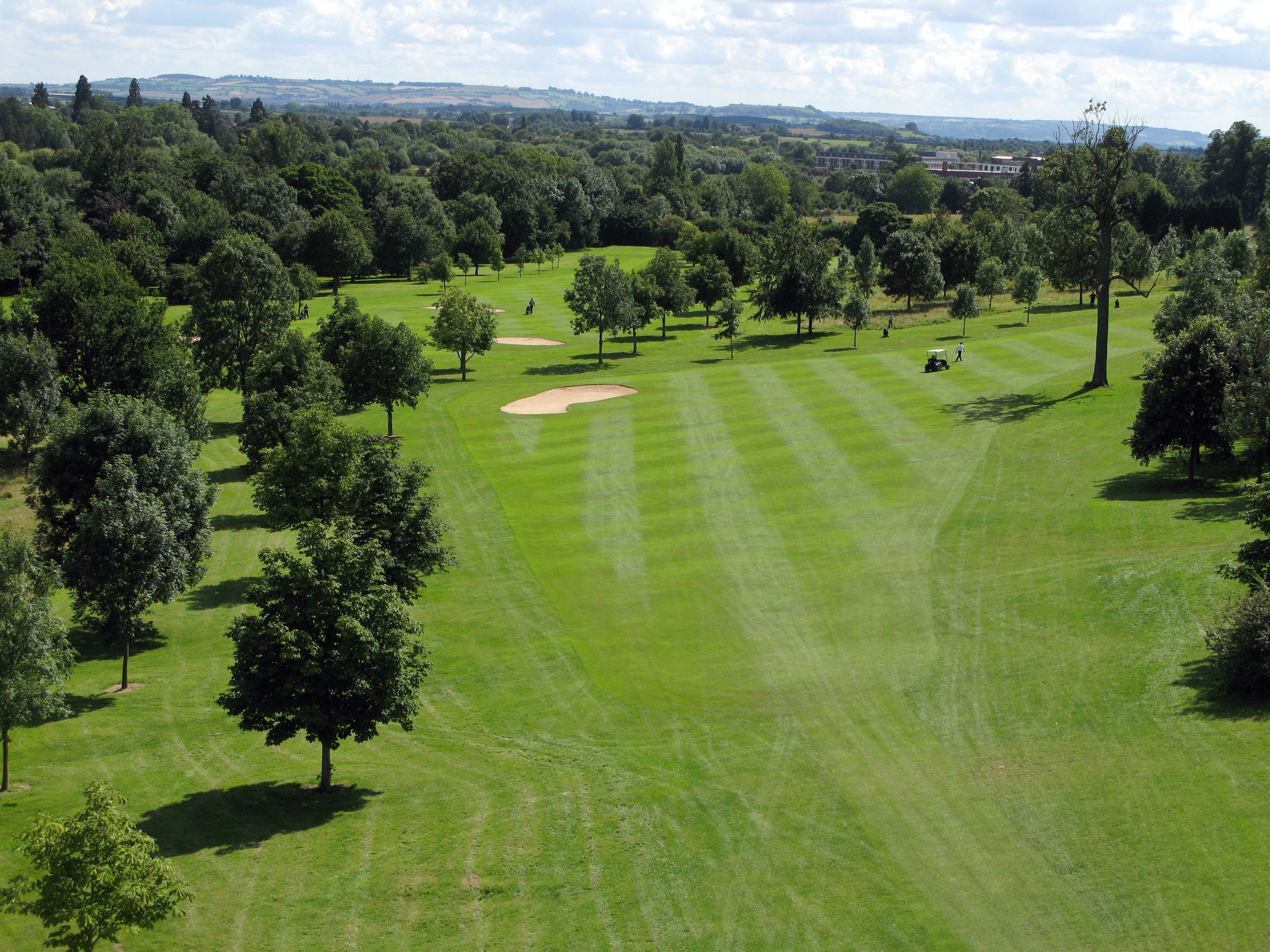Un campo de golf con fairways bien cuidados, búnkeres de arena y una variedad de árboles.