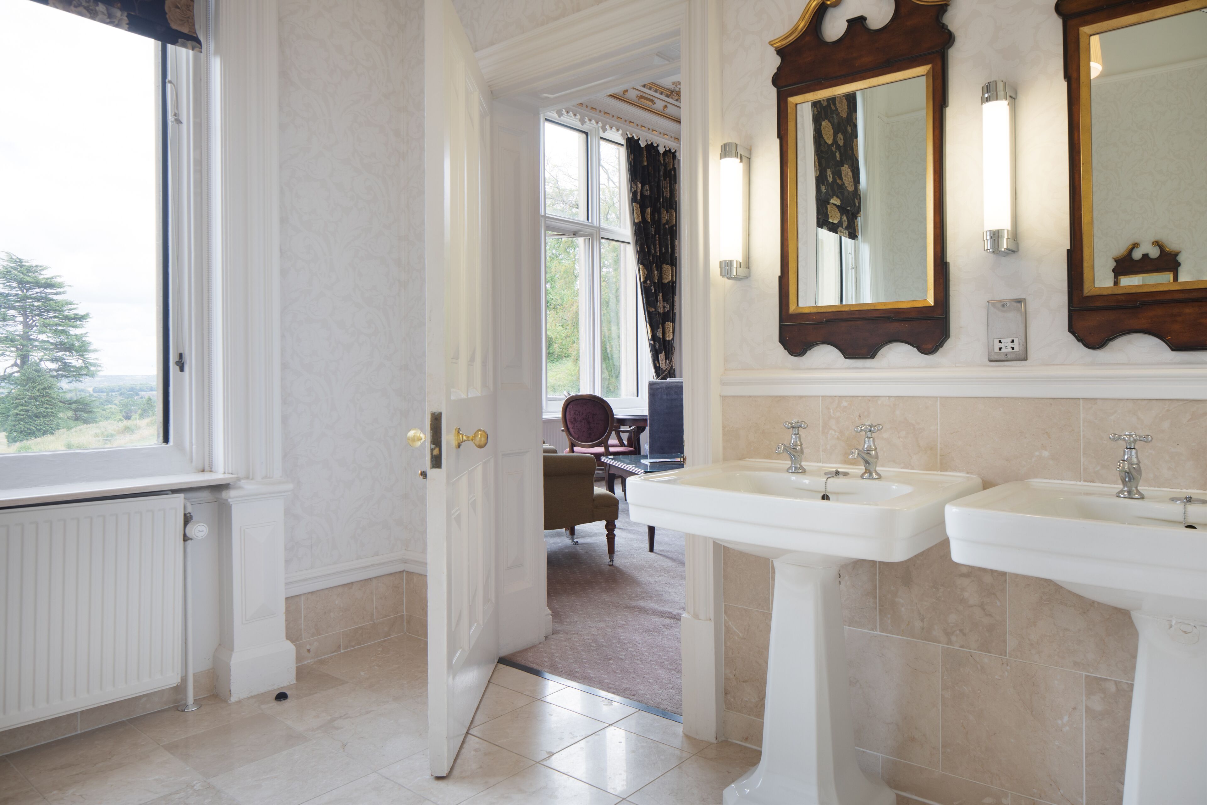 Une salle de bain avec deux lavabos, un miroir et une fenêtre.