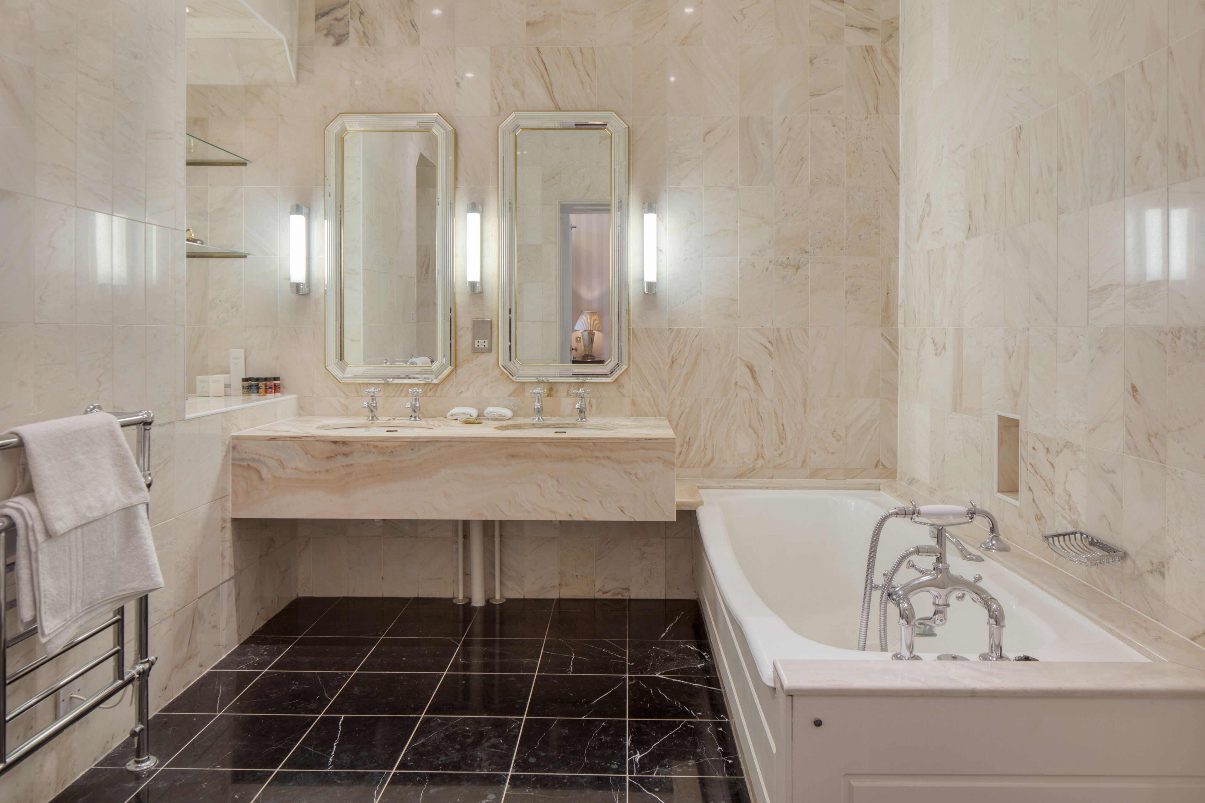 A modern bathroom with two sinks, a large bathtub, and marble walls.
