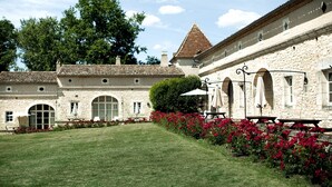 A stone building with a courtyard, arched windows, and a tiled roof. - Château des Vigiers (Monestier)