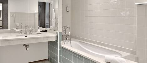 A modern bathroom with two sinks, a bathtub, and a large mirror.