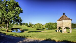 A stone gazebo with a tiled roof, surrounded by a well-maintained lawn and trees. - Château des Vigiers (Monestier)