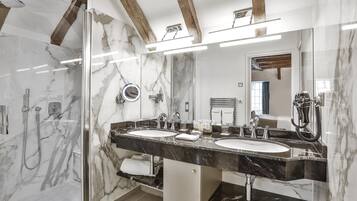 A modern bathroom with two sinks, a glass shower enclosure, and a large mirror.