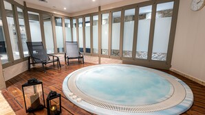 A hot tub with a wooden deck, two lounge chairs, and a view through large windows. - Château des Vigiers (Monestier)