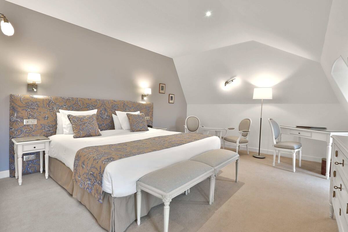 A bedroom with a large bed, bedside tables, a desk, and a chair.