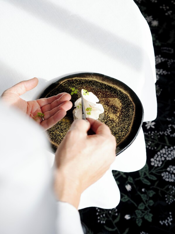 A person holding a spoon over a bowl with a dark, speckled interior.