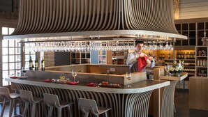 A bar area with a central island, bar stools, and a bartender.