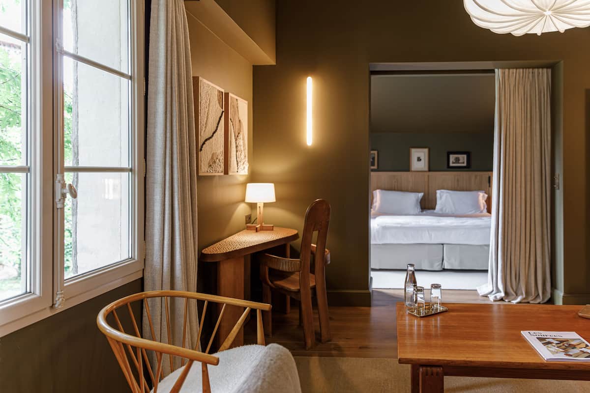 Une chambre d’hôtel avec un bureau en bois, une chaise, un lit et une vue sur l’extérieur.