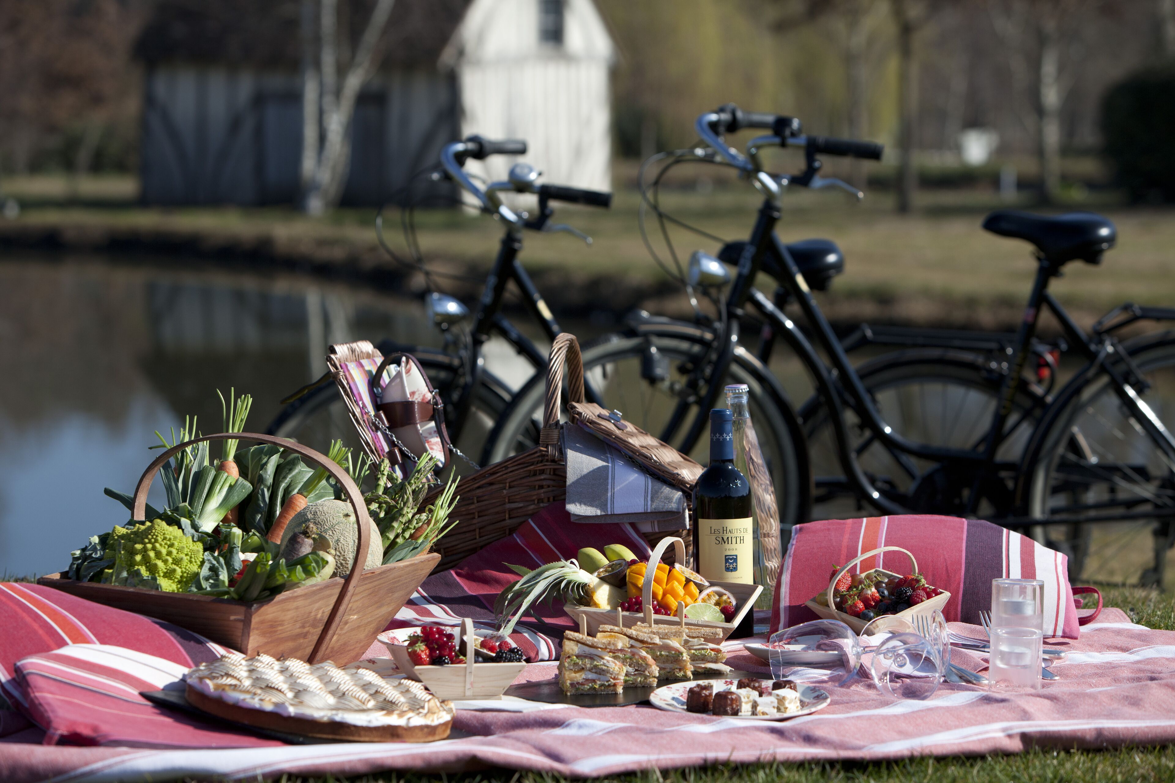 A picnic setup with food, drinks, and bicycles by a lake.