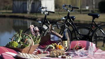 A picnic setup with food, drinks, and bicycles by a lake.
