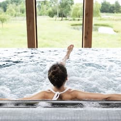 Relax in a tranquil space with a hot tub and serene views of the lush landscape.