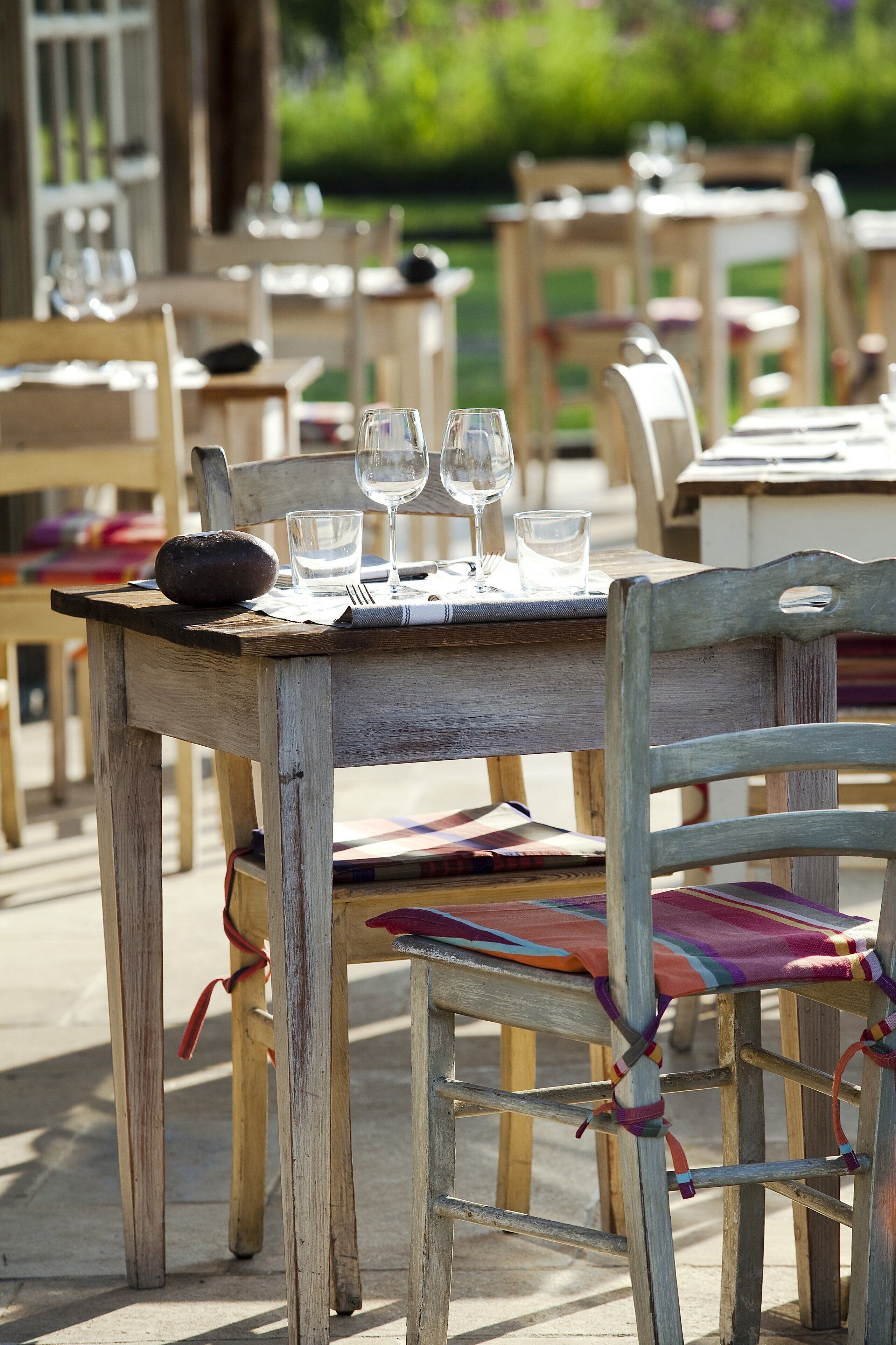 A wooden outdoor dining table with chairs, set for a meal.