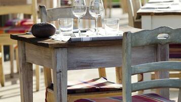A wooden outdoor dining table with chairs, set for a meal.