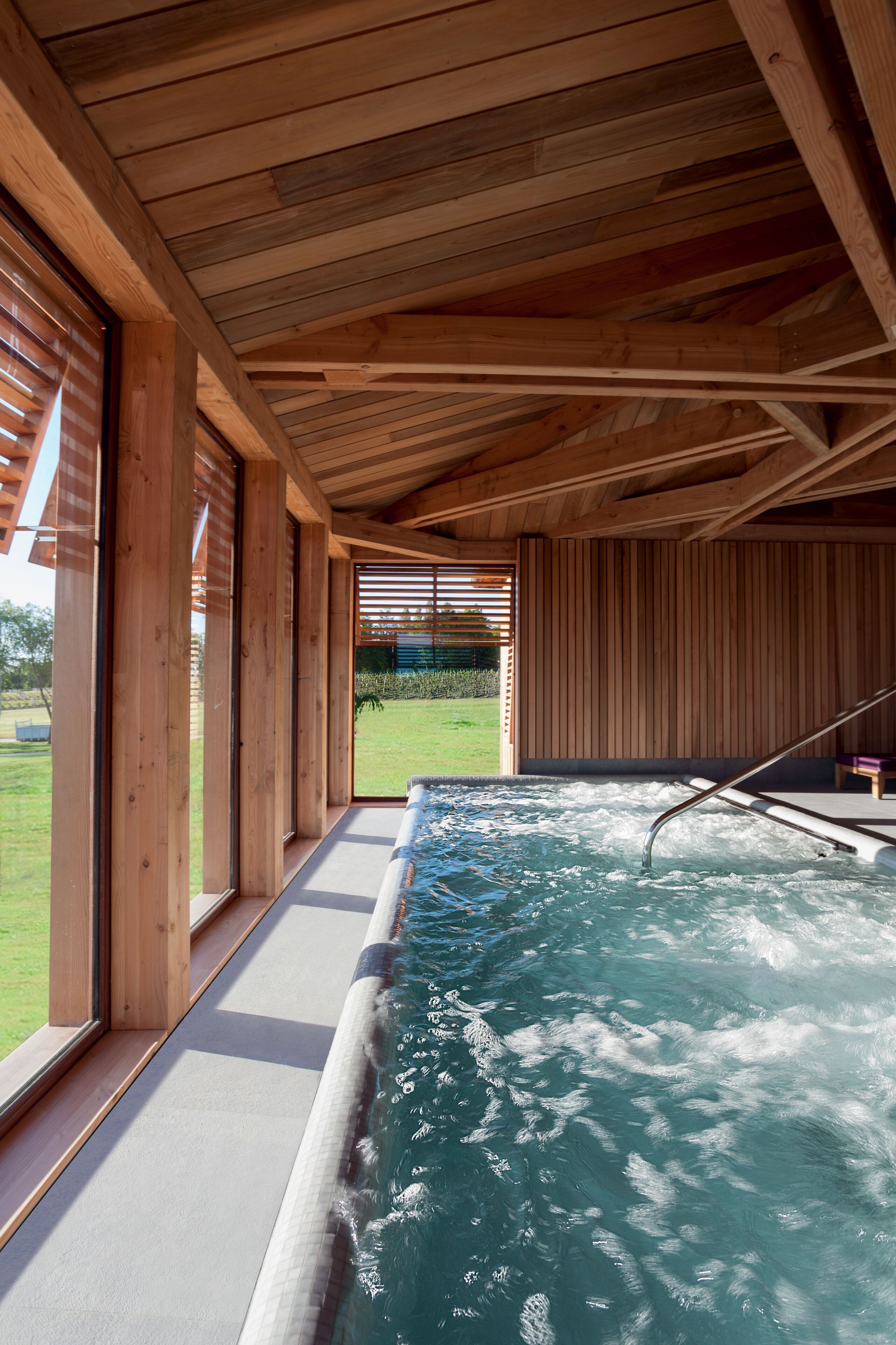 A spa area with a hot tub, wooden beams, and large windows.