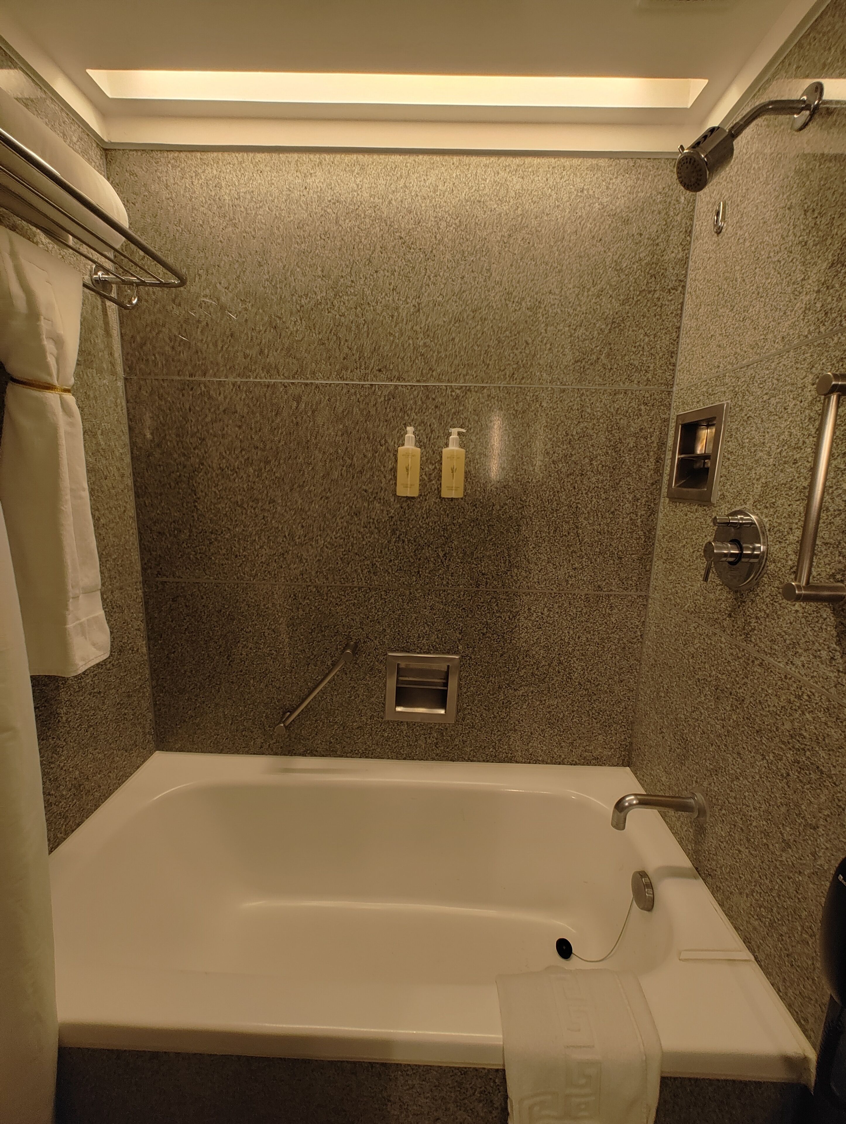 Et moderne badeværelse med et fristående badekar, et håndklædetørrestativ og to shampoo flasker på væggen.