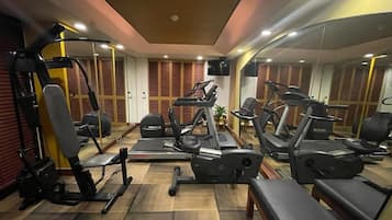 Uma academia com equipamentos de exercícios, espelhos e piso de madeira.