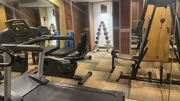 Un gimnàs amb cintes de córrer, màquines de musculació i un mirall.