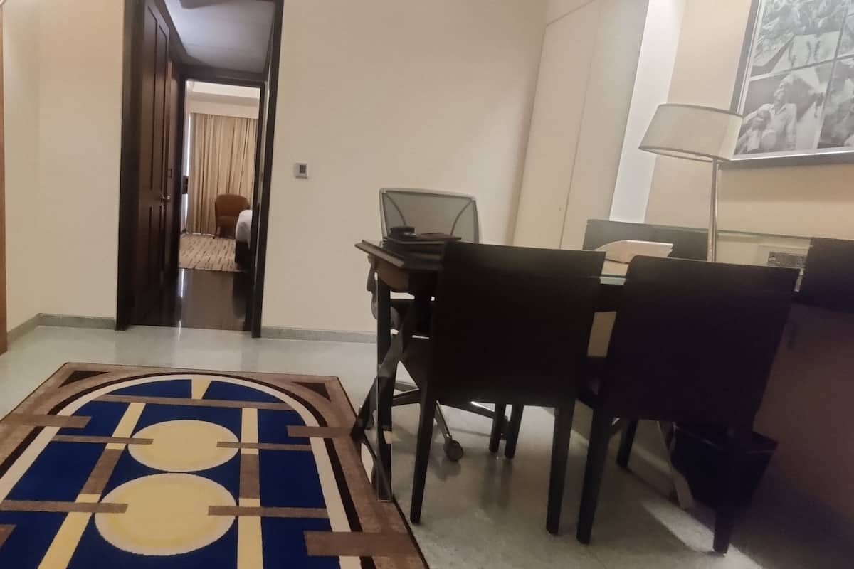 Quarto de hotel com área de jantar, uma cama e um corredor que dá para outro quarto.