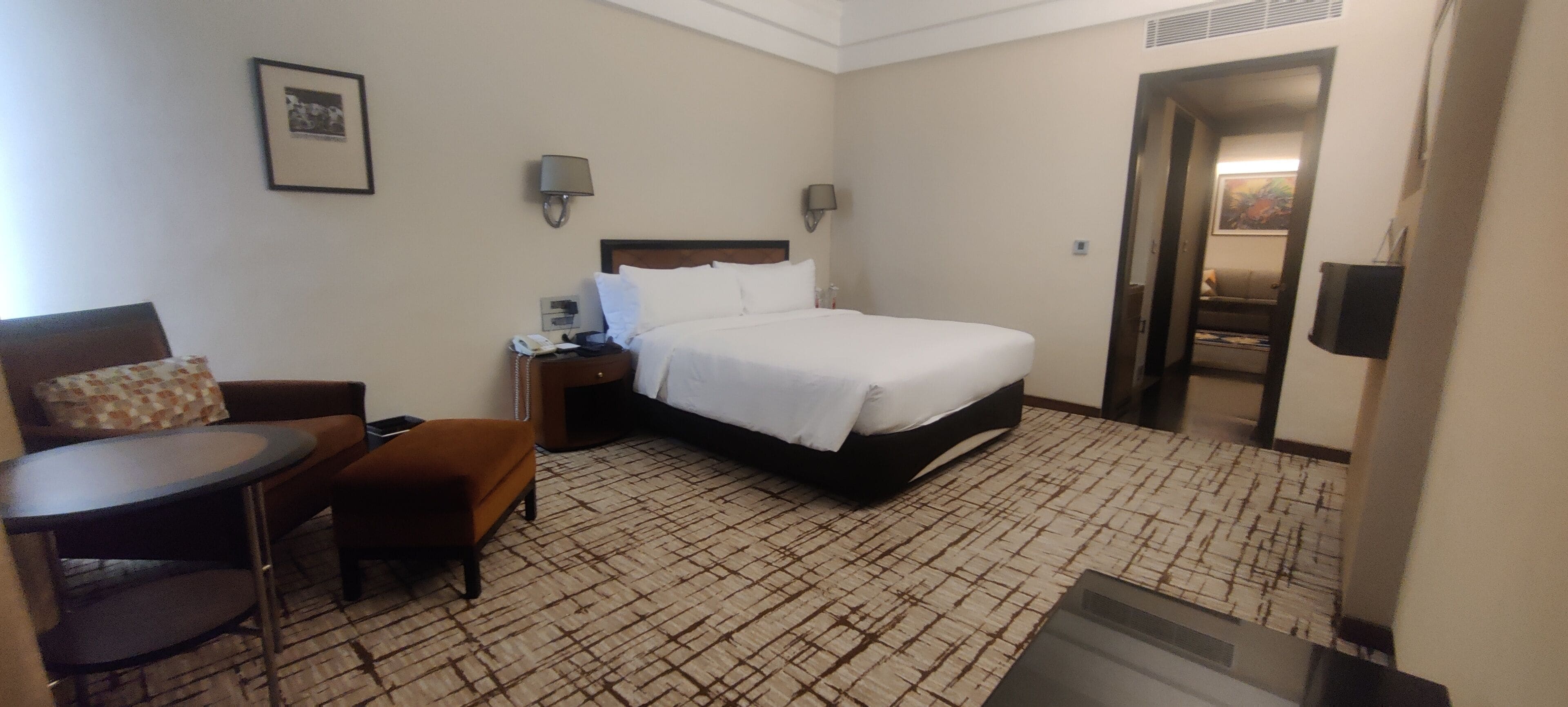 A hotel room with a bed, a desk with a chair, a small table, and a sofa.