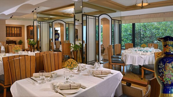 A restaurant with multiple tables set for dining, featuring white tablecloths and wooden chairs. - Hotel Marine Plaza Mumbai (Mumbai)