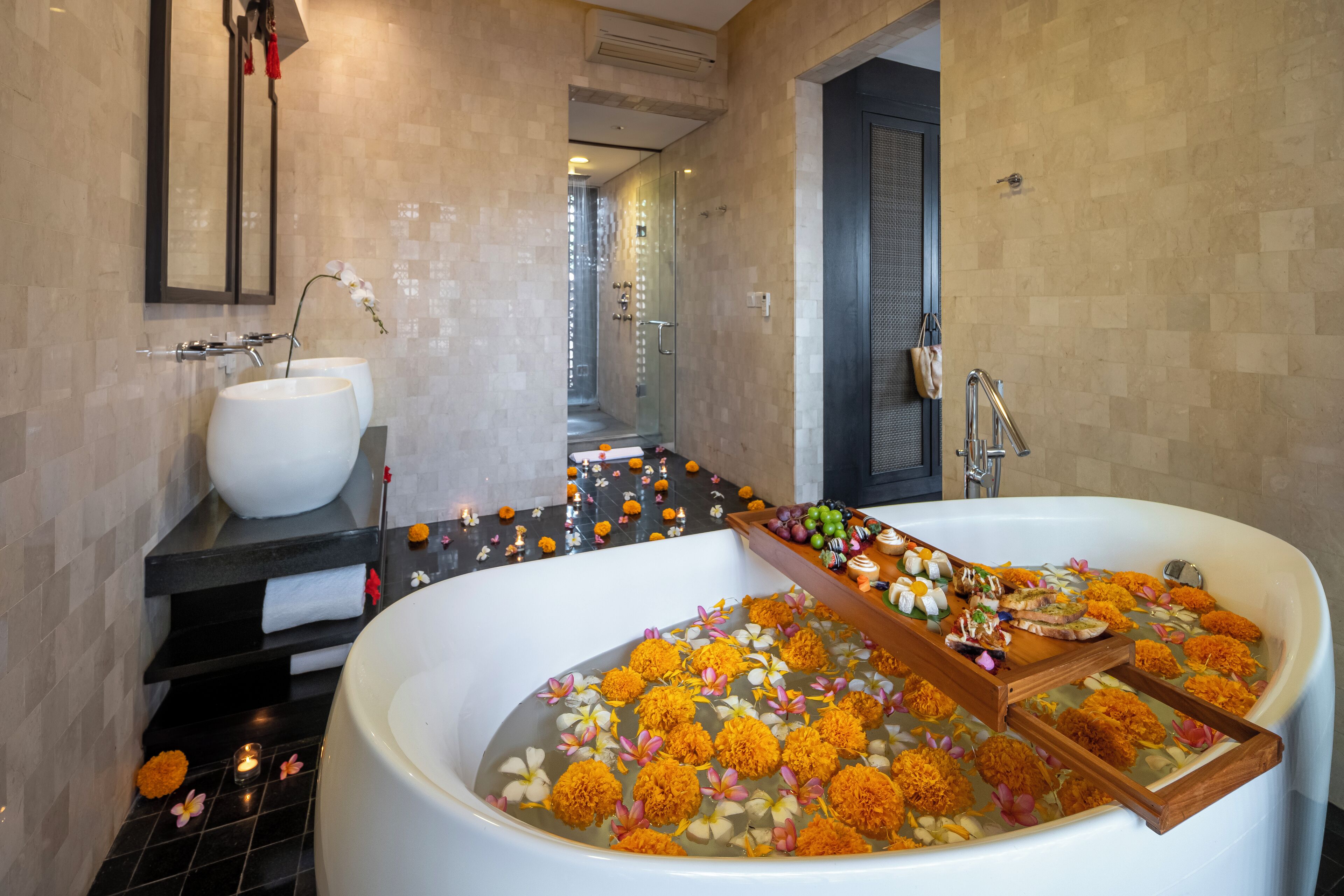 A bathroom with a large bathtub filled with flowers, a sink, and a mirror.