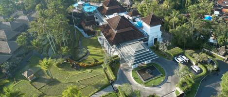 An aerial view of a residential area with houses, a swimming pool, and lush greenery.
