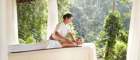 A massage therapy session in a room with a view of lush greenery.