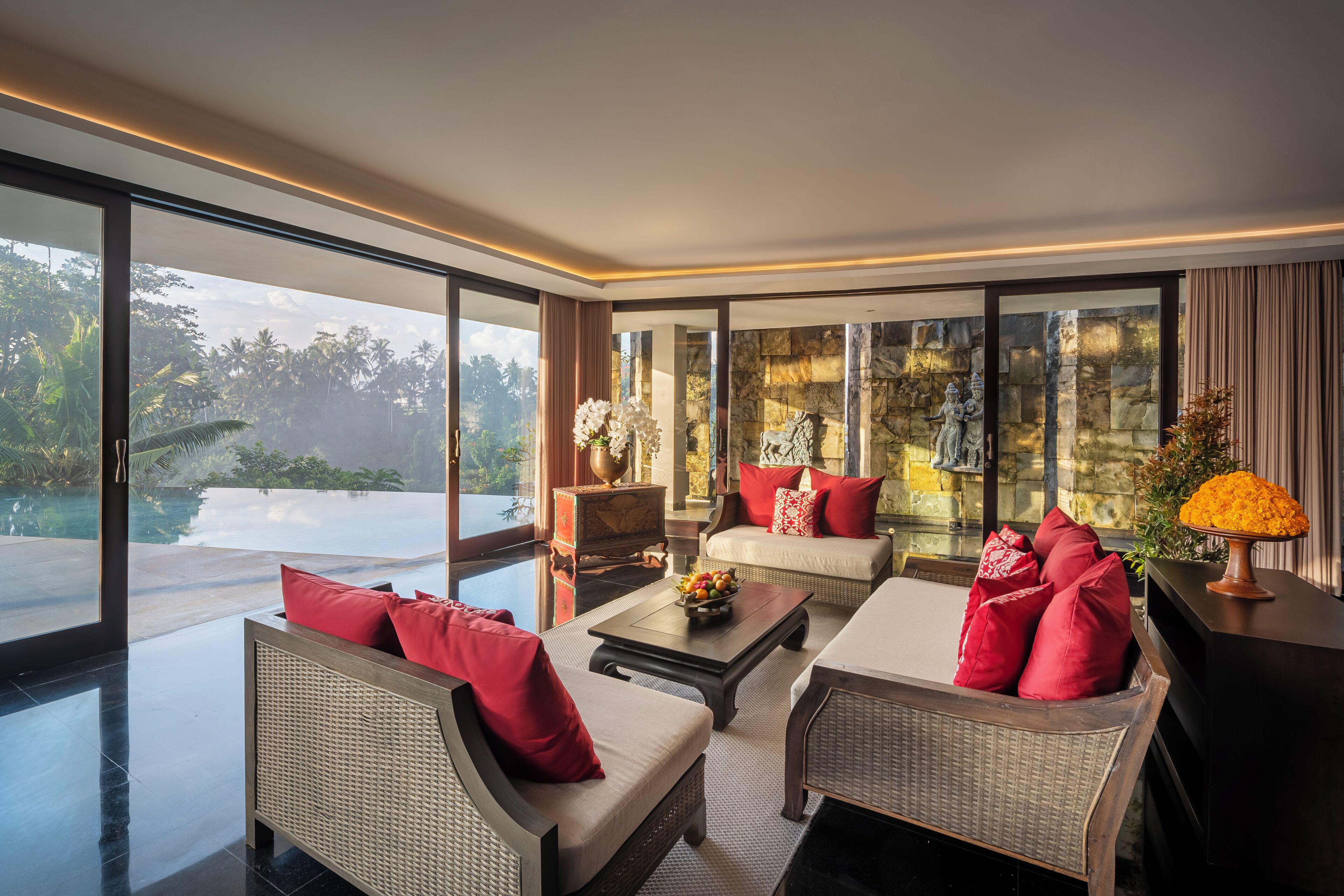 A modern living room with a view of a pool and greenery.