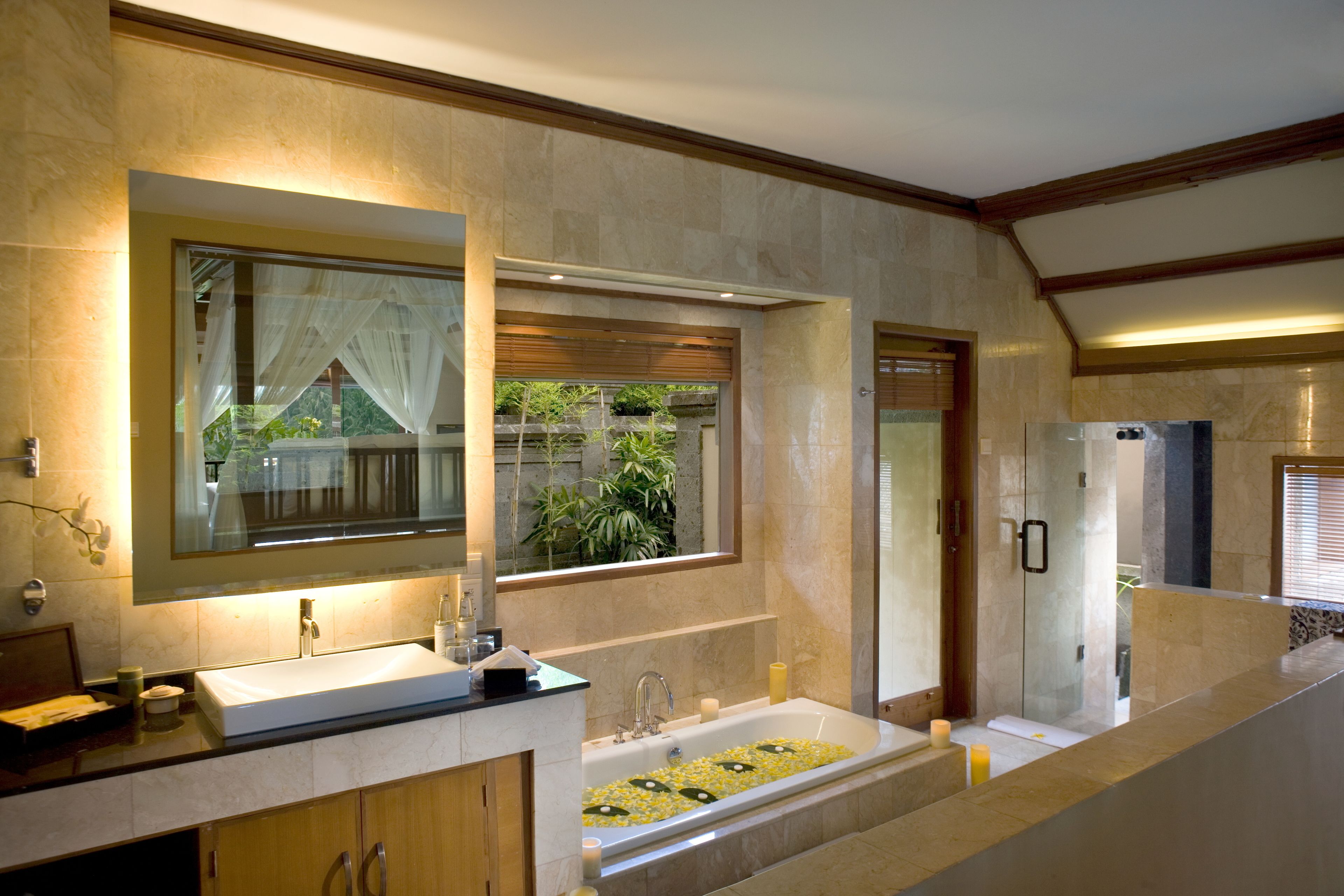 Une salle de bain moderne avec un grand miroir, une baignoire décorée de fleurs jaunes, une douche et un réfrigérateur.