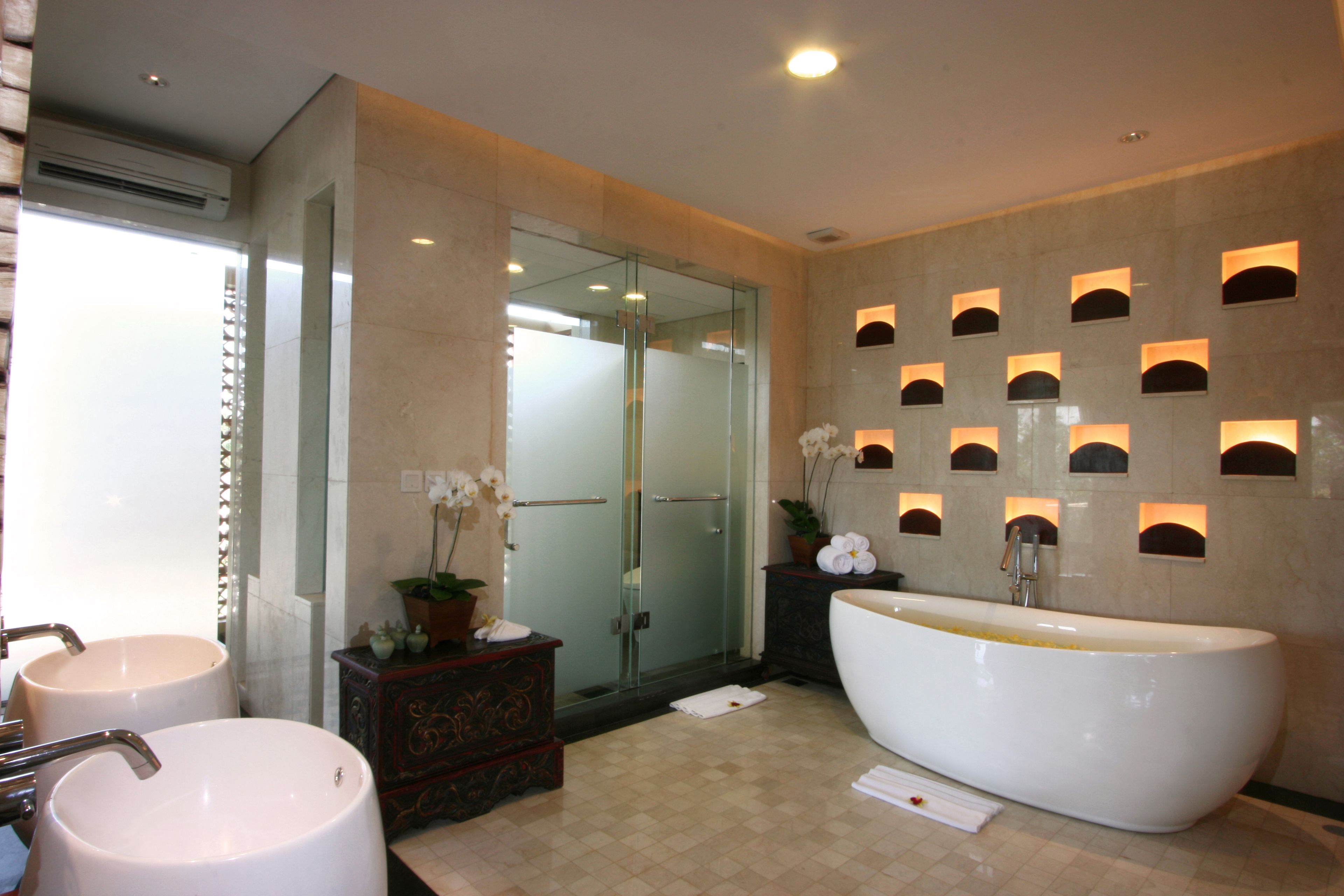 A modern bathroom with two sinks, a large bathtub, and a glass shower enclosure.