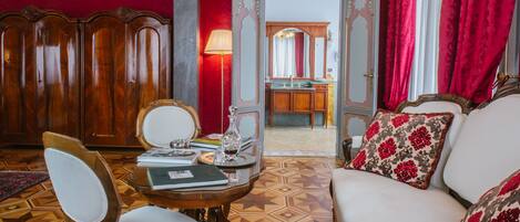 Una habitación con cabecera de madera, sofá blanco con cojines estampados, una mesa de madera con lámpara y piso con diseño.