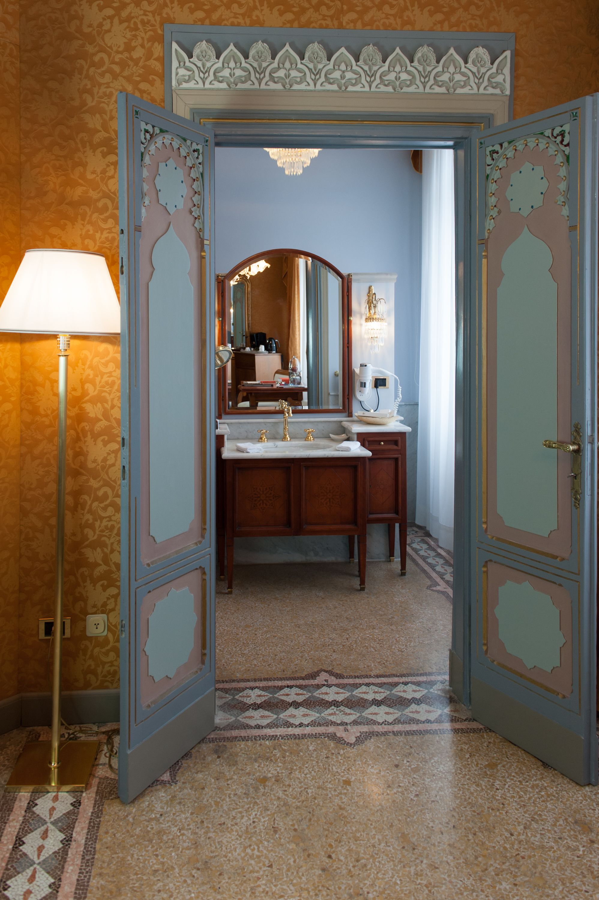 Un bagno con doppio lavabo, uno specchio e una lampada da terra.