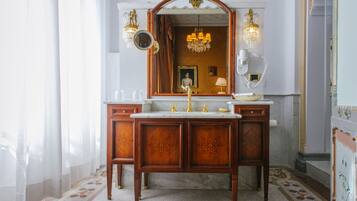 A classic bathroom with a marble sink, ornate wooden cabinetry, and a large mirror.
