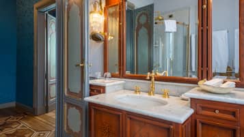 A luxurious bathroom with two sinks, ornate wood cabinetry, and a large mirror.