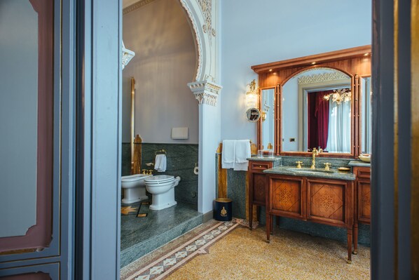 A bathroom with a marble floor, wooden vanity, and a large mirror.