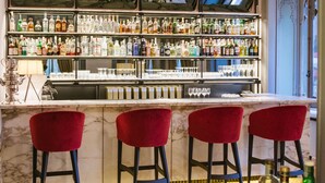 A bar area with marble countertops, red bar stools, and a variety of liquor bottles.