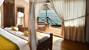 Une chambre avec vue sur la mer, un plancher en bois et un balcon équipé d’une table et de chaises.