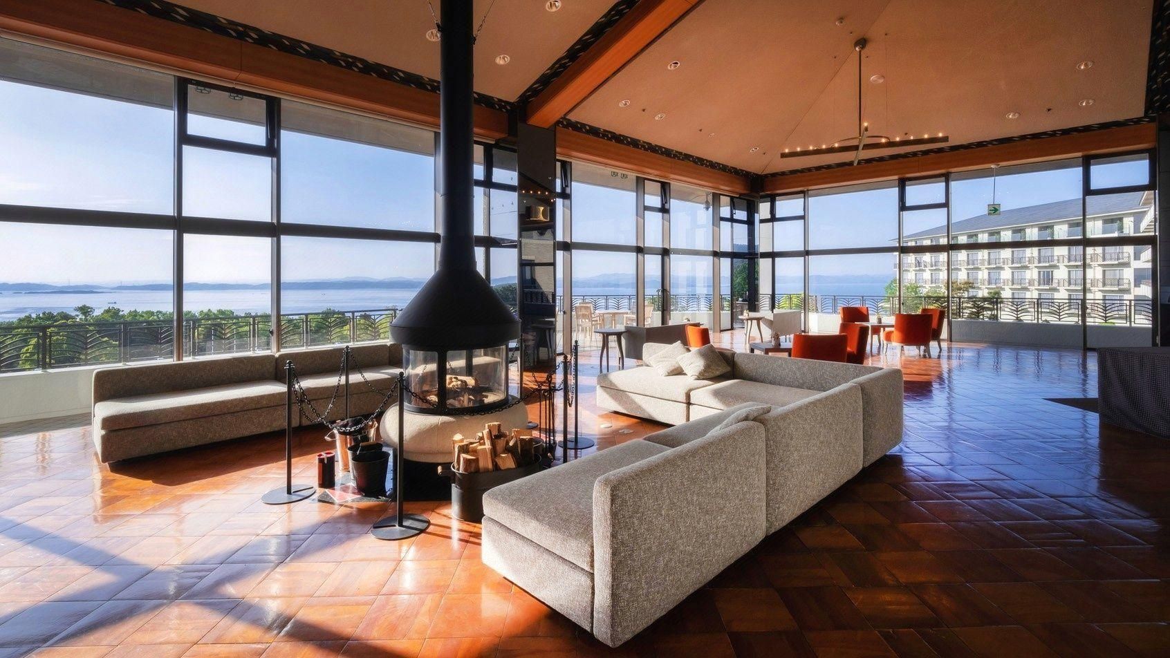 Un amplio espacio habitable con un ventanal grande, una chimenea y un conjunto de asientos.